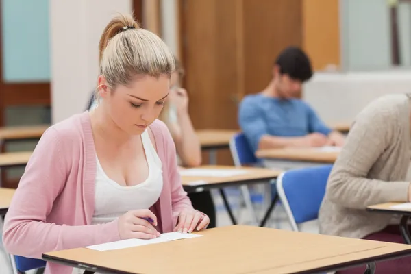 Woman writing note in classroom Stock Photo