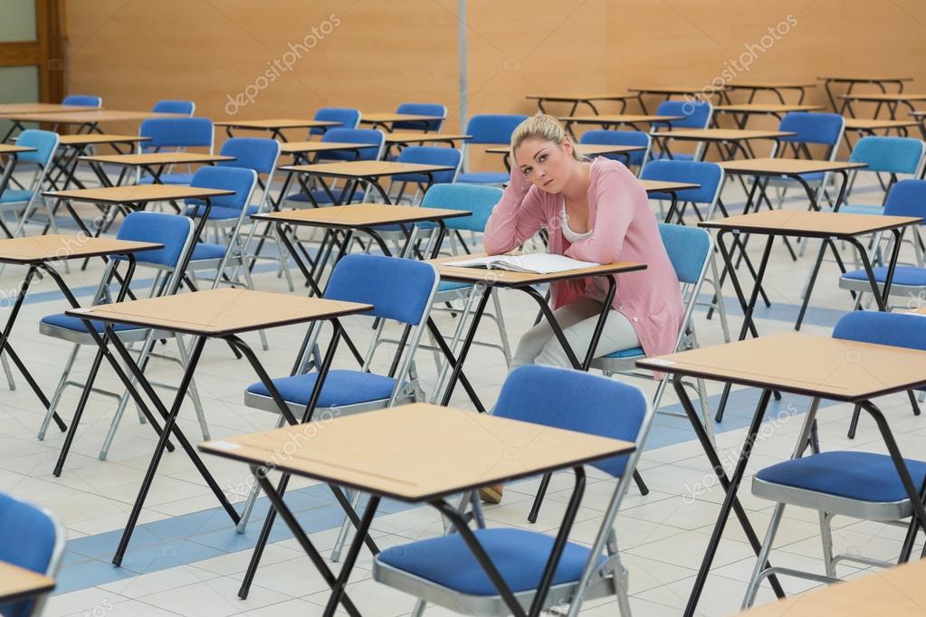 Student sitting at desk in empty exam hall — Stock Photo
