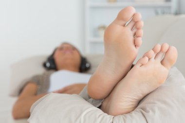 Woman with her feet up listening to music clipart