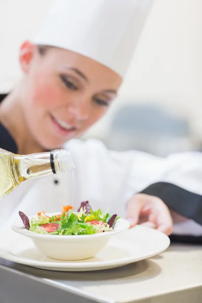 Chef-kok olijfolie gieten over salade — Stockfoto