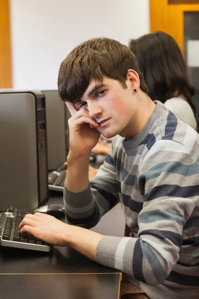 Студент выглядит уставшим в компьютерной комнате — стоковое фото