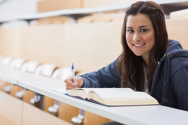 Meisje vergadering glimlachen terwijl het lezen van een boek en nemen notes — Stockfoto