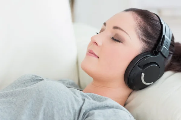 편안한 여자는 소파에 누워 음악을 듣고 — 스톡 사진