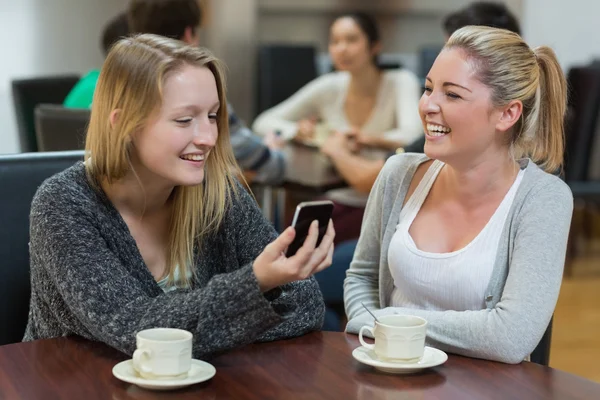 Kvinnor sitter på kafé titta på smartphone — Stockfoto