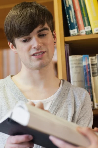 Hombre que se muestra libro en la biblioteca —  Fotos de Stock