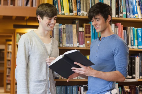 Estudantes em pé na biblioteca olhando para o livro — Fotografia de Stock