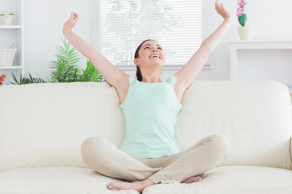 Sorglös kvinna sitter i soffan och stretching — Stockfoto