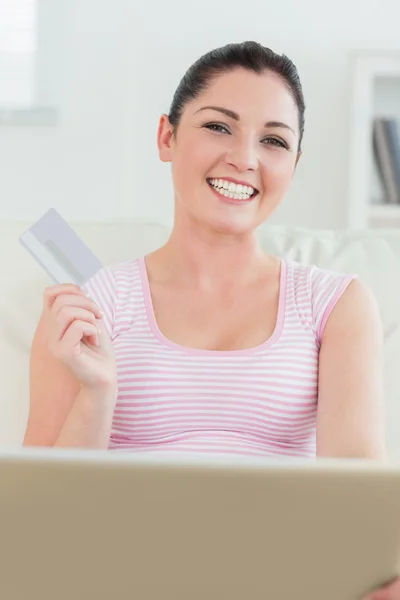 Frau sitzt mit Laptop und Kreditkarte auf einer Couch — Stockfoto