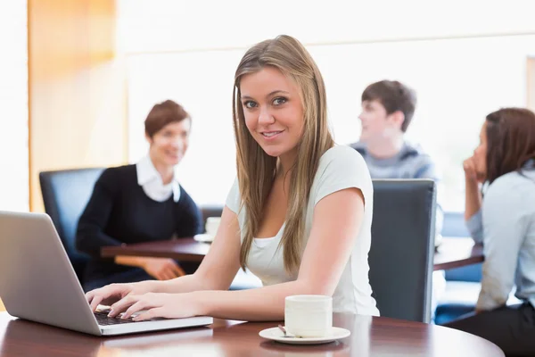 Mulher sentada na cafetaria à mesa usando laptop — Fotografia de Stock