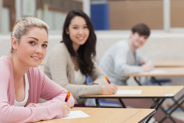 Étudiants levant les yeux de l'examen et souriant — Photo