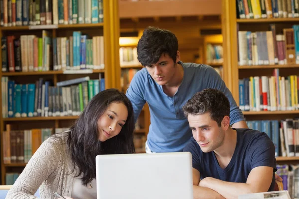 Studenten kijken iets op laptop in bibliotheek — Stockfoto