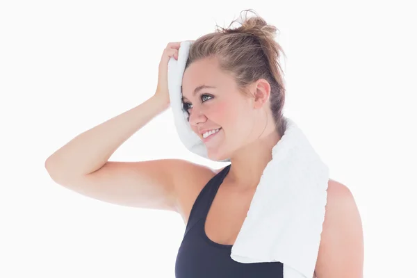 Mujer sonriendo mientras sostiene la toalla en su frente — Foto de Stock