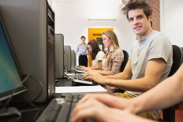 Étudiants assis à la salle informatique avec un homme souriant — Photo