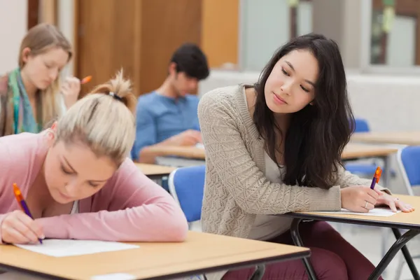 Dziewczyna kopiowanie innej pracy studentów w egzamin — Zdjęcie stockowe