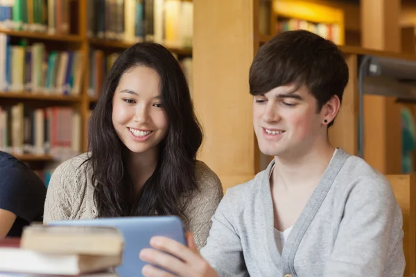 Estudantes sentados na biblioteca segurando um tablet pc — Fotografia de Stock