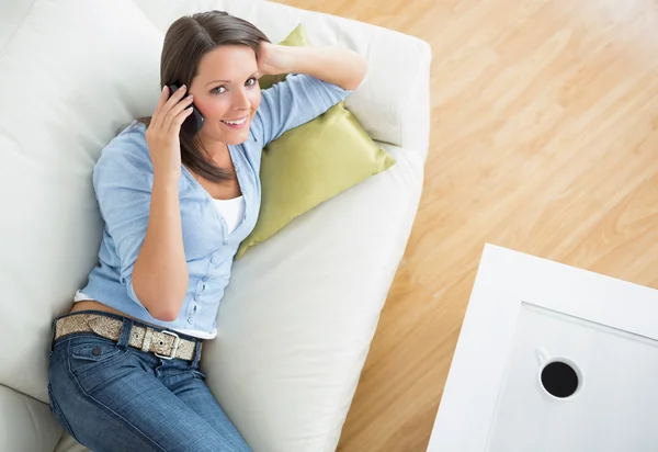 Brunette woman lying on sofa and calling — Stock Photo, Image