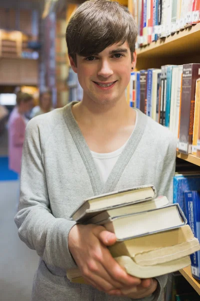 Студент, стоящий на книжной полке — стоковое фото
