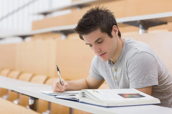 Studente seduto a leggere un libro e prendere appunti — Foto Stock