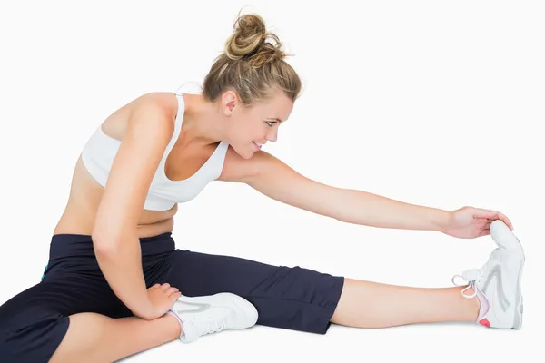 Kvinna sitter medan stretching ben — Stockfoto