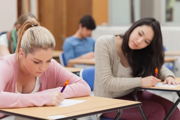 Morena está tratando de copiar rubia estudiante en el examen —  Fotos de Stock