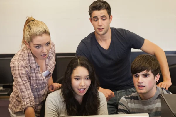 Students sitting at the computer looking shocked — Stock Photo, Image