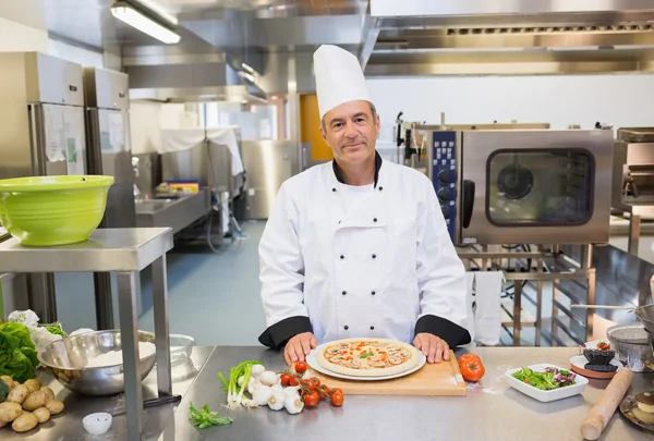 Chef standing in the kitchen with pizza — Stock Photo, Image