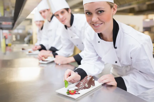 Glimlachen van chef-kok afwerking dessert platen — Stockfoto