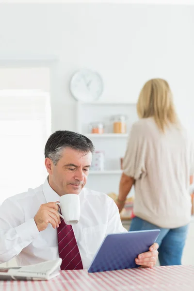 Man sitting at the kitchen with tablet pc and coffee — ストック写真