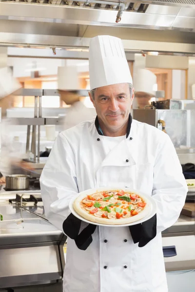 Chef showing pizza in busy kitchen — Stock Photo, Image
