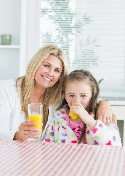 Femme et enfant assis à la table de la cuisine tenant un verre de — Photo