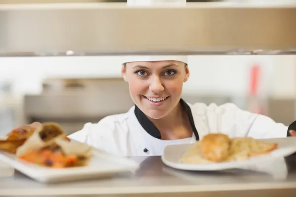 Chef handing dinner plates through order station — Stock Photo, Image