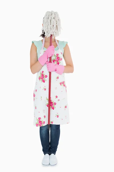 Woman wearing apron hiding her face with a mop — Stock Photo, Image