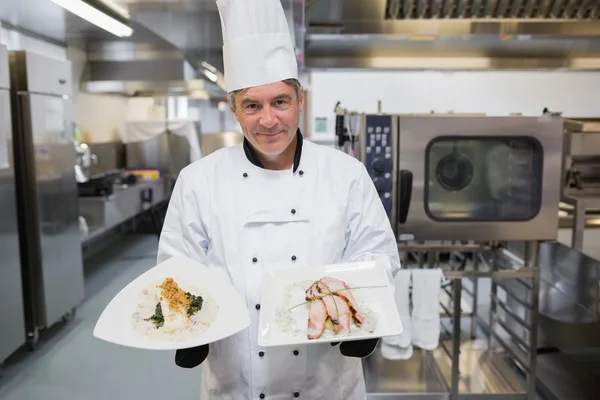 Sorrindo cozinheiro segurando duas placas — Fotografia de Stock
