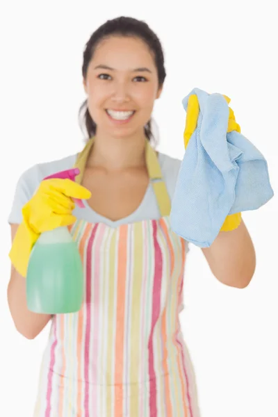 Smiling woman holding up rag and spray bottle — Stock Photo, Image