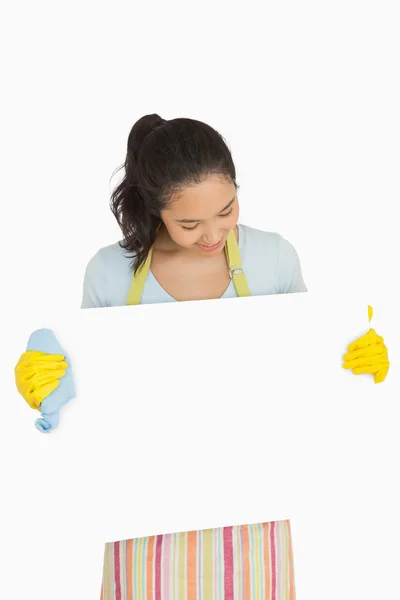 Woman in rubber gloves looking at white surface she is holding — Stock Photo, Image