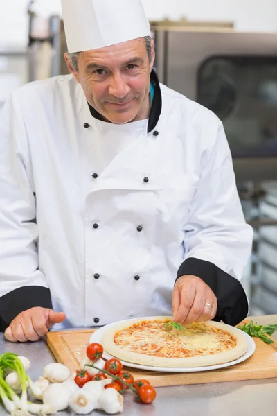 Happy chef giving finishing touch to pizza — Stock Photo, Image