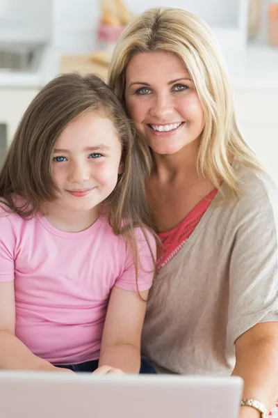 女性と娘のラップトップに笑みを浮かべて座っています。 — ストック写真