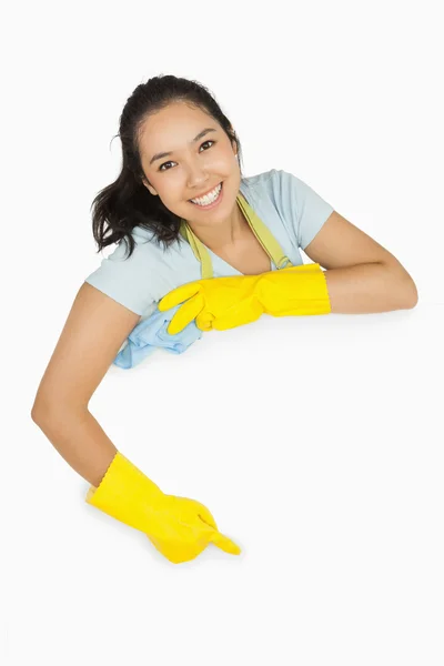 Senhora de limpeza feliz apontando para a superfície branca — Fotografia de Stock