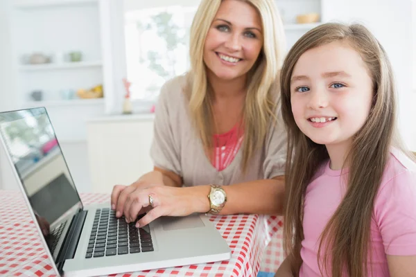 Жінка друкує на ноутбуці з дочкою — стокове фото