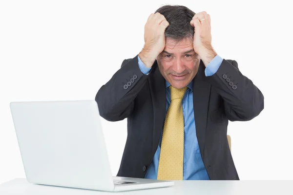 Hombre problemático sentado en su escritorio con una computadora portátil —  Fotos de Stock