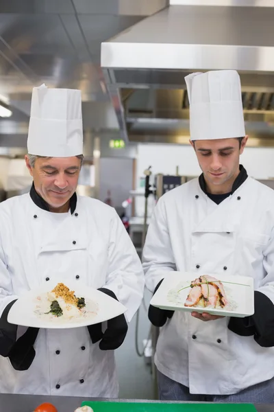 Dos cocineros orgullosamente presentando sus comidas —  Fotos de Stock