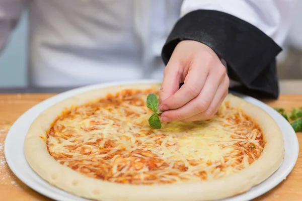 Basil leaf being put on pizza — Stock Photo, Image