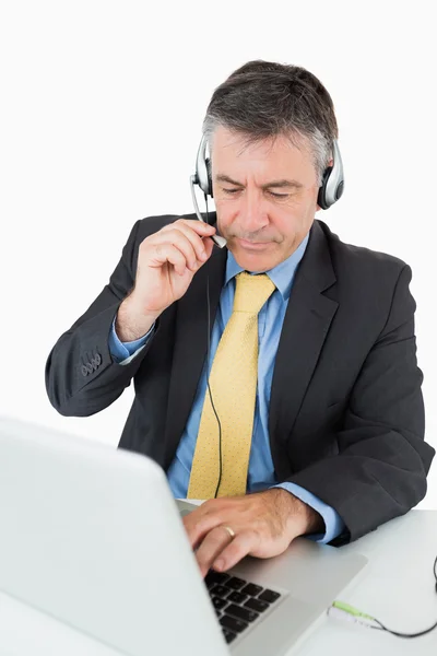 Man sitter vid sitt skrivbord med hörlurar — Stockfoto