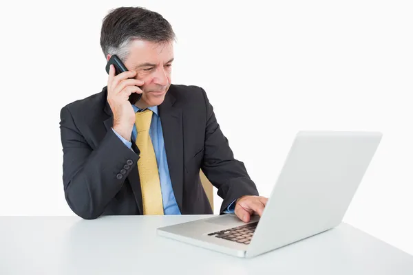 L'uomo che telefona mentre scrive sul computer portatile — Foto Stock