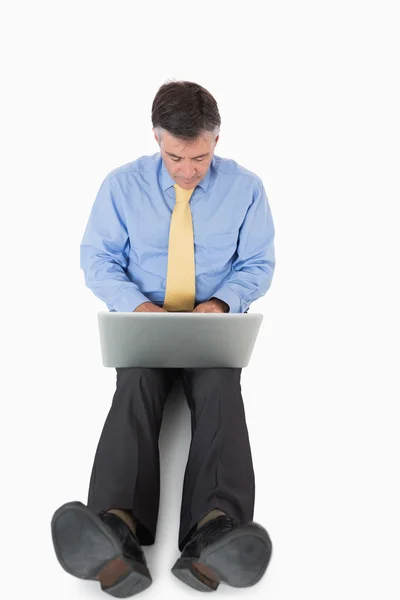 Businessman sitting on floor working on laptop — Stock Photo, Image