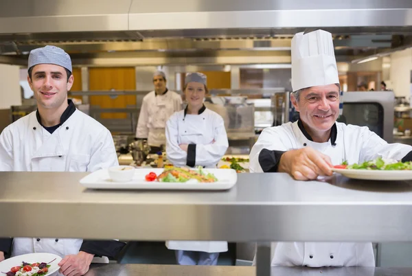 Smiling chef putting salad on order station — Stock Photo, Image