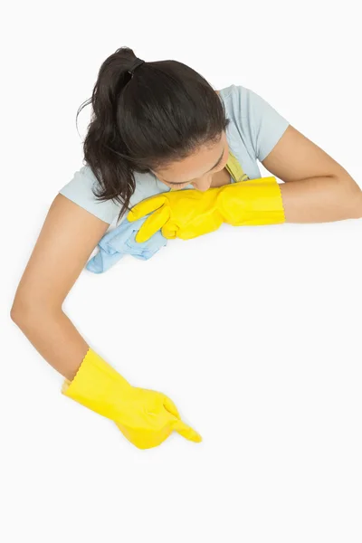Женщина в резиновых перчатках, указывающая на белую поверхность — стоковое фото