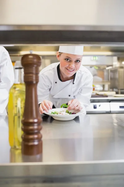 Smiling chef garnishing a salad and looking up — Stock Photo, Image