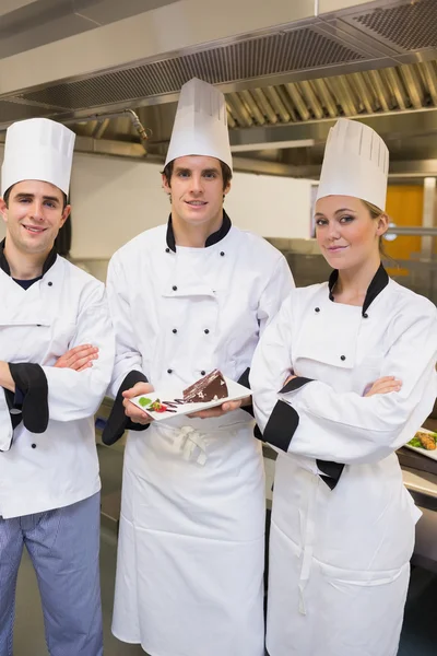 Três Chef feliz está apresentando um bolo — Fotografia de Stock