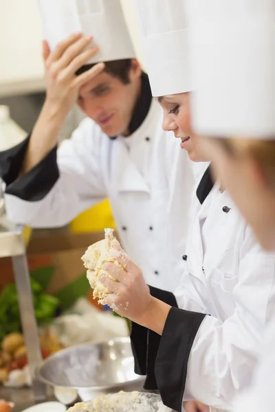 Un chef pétrissant la pâte tandis que d'autres regardent — Photo